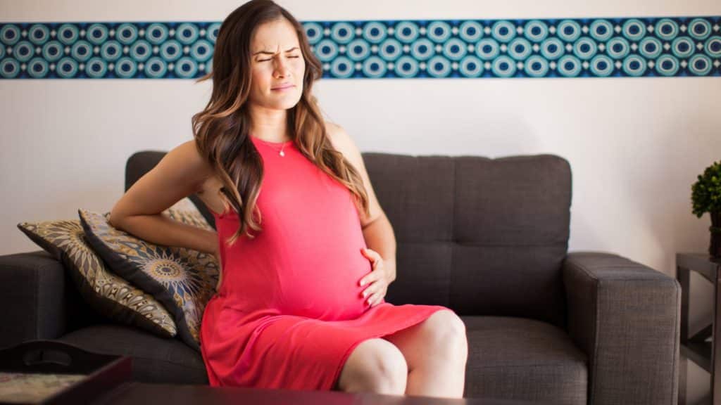 Pregnant Lady Sitting On Couch With Pain