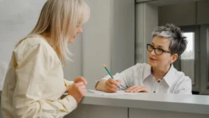 A Receptionist Is Holding A Pencil And Looking At A Patient